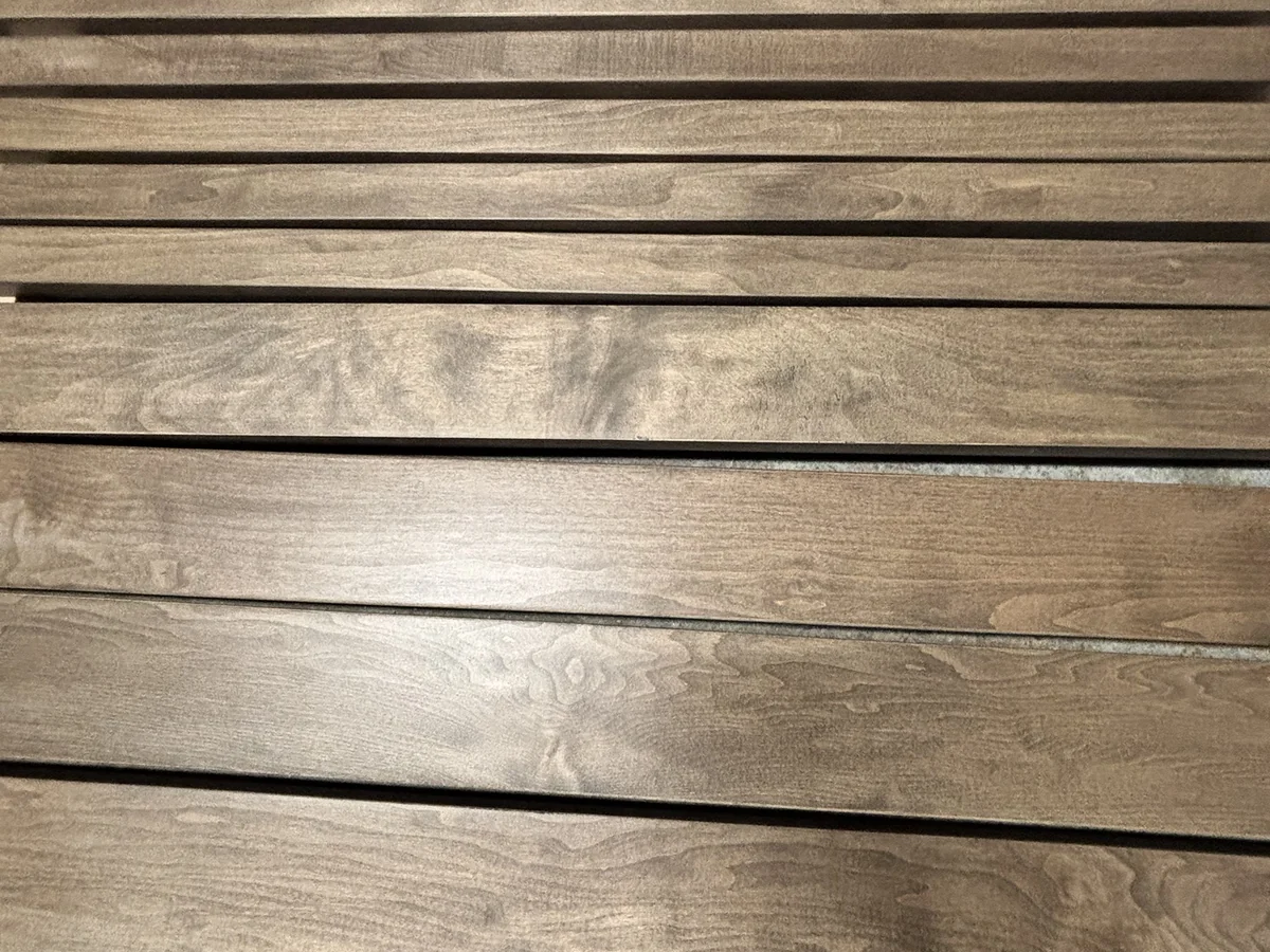 Spray-finished boards in a rich brown stain, laid out to cure